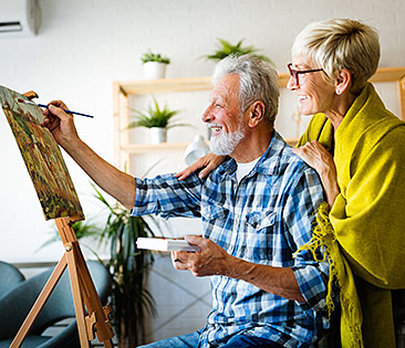 Pensionsfonds - Frau steht hinter ihrem malenden Mann